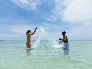 a couple splashes playfully in calm green gulf waters at the beach