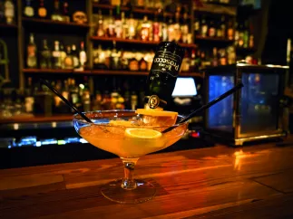 A photo of a pink cocktail with two straws on a bar