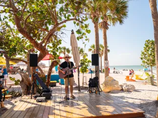 a man in a tshirt and hat playing guitar on a wooden deck at Paradise Grille in Pass-a-Grille Beach