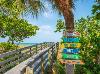 a sign encouraging beach visitors to leave only their footprints, placed near a boardwalk to Indian Rocks Beach