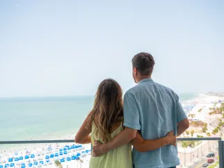 A couple looks out at the balcony of a beachfront resort