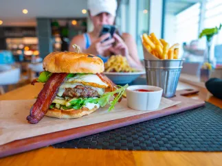 a big juicy burger with cheese and bacon on a wooden board with a metal bucket full of fries at BRGR Kitchen & Bar in Treasure Island