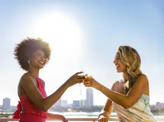 two women toast with cocktails at Pier Teaki rooftop bar at the St. Pete Pier