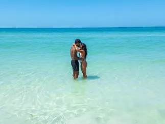 a couple kissing while standing in clear turquoise waters at the beach