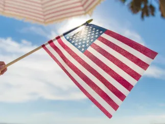 someone holding an American flag at the beach