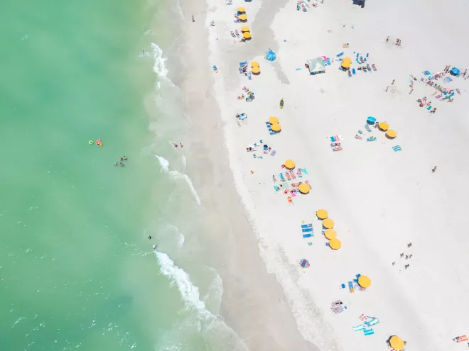 Aerial view of yellow beach cabanas and emerald-green waters of Treasure Island.