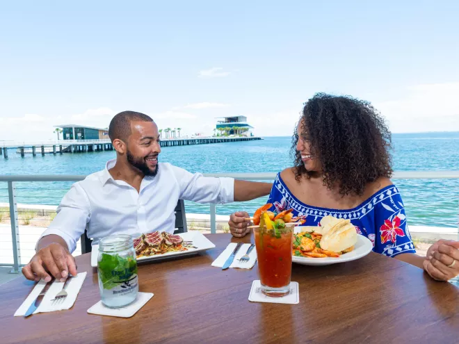 A couple dines and enjoys cocktails at Doc Ford's Rum Bar & Grille with the St. Pete Pier in the background