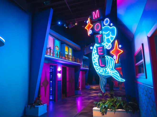 A neon sign outside an artistic replica of a vintage Florida hotel