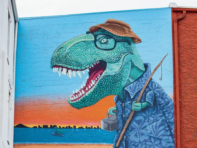 a mural depicts a tyrannosaurus rex dressed as if he is going fishing with a fishing pole, hat and tackle box. In the water behind him, a smaller dinosaur rides a jet ski