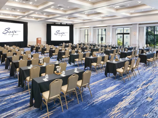 A room with chairs and tables facing two screens.
