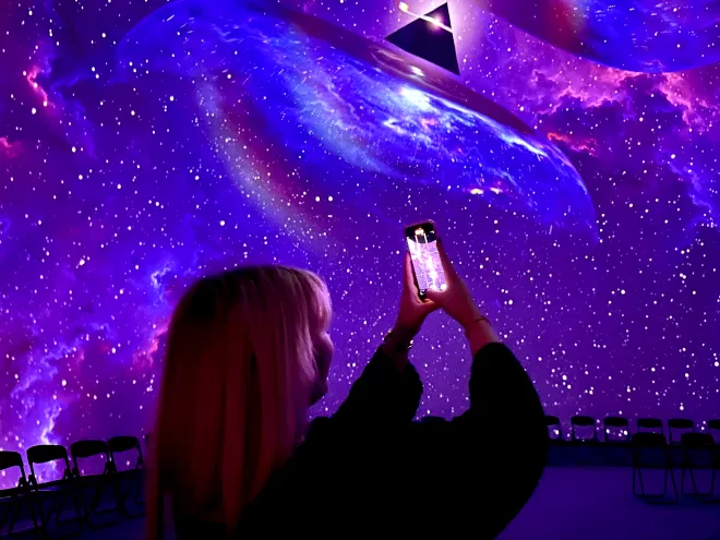 A woman takes a picture of an artistic Pink Floyd visual