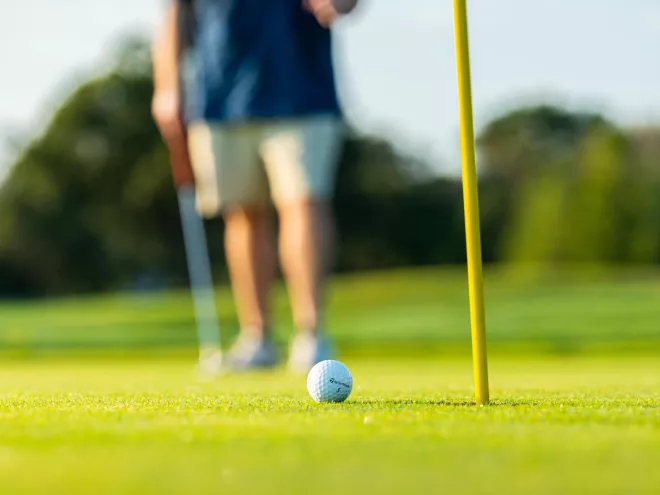 A golfer and golf ball near the hole