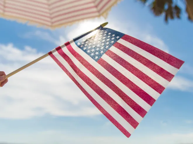 someone holding an American flag at the beach