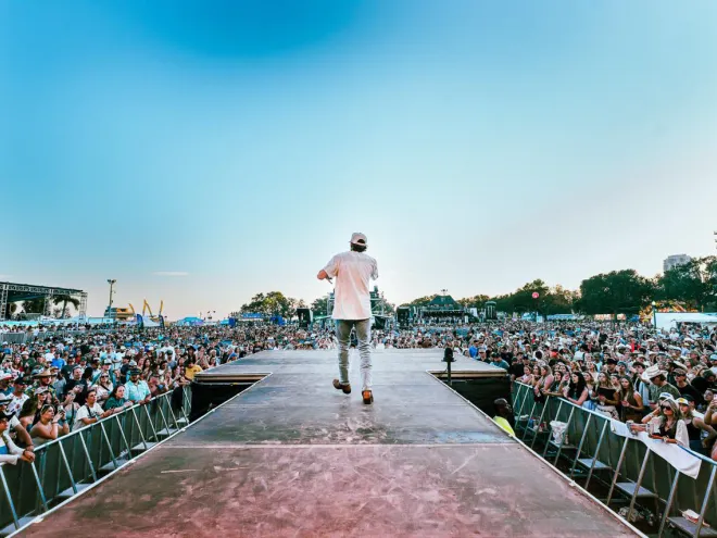 Performer on stage at St. Pete Country Music Fest with a large, festive crowd.