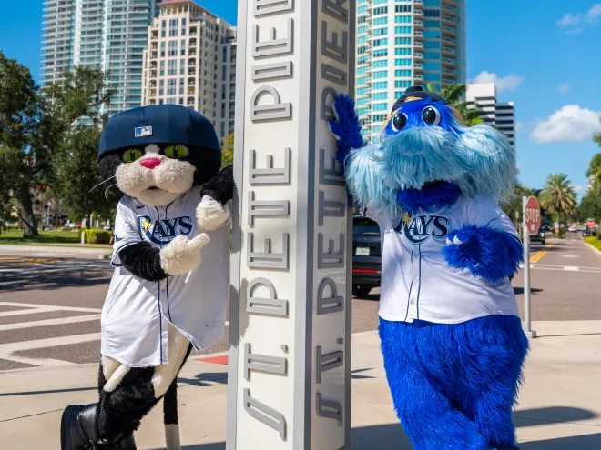 the rays mascots standing next to a sign at the St. Pete Pier