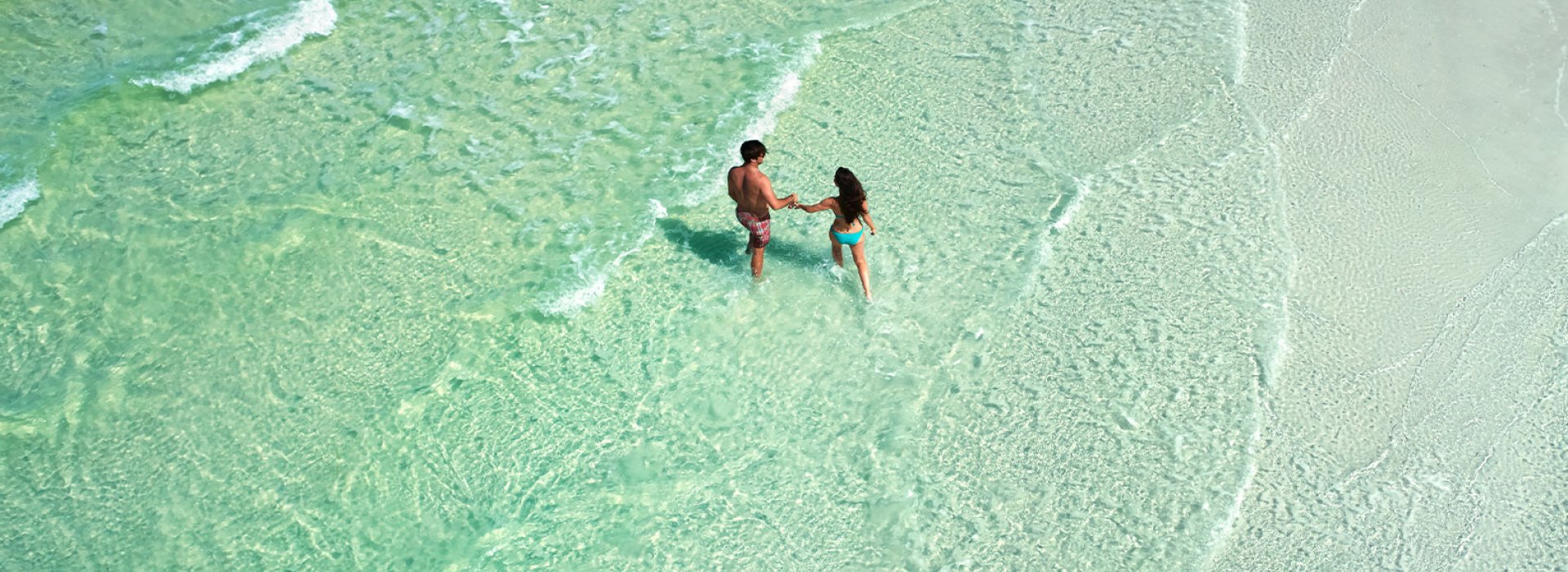 A couple walking in the emerald-green waters of Anclote Key