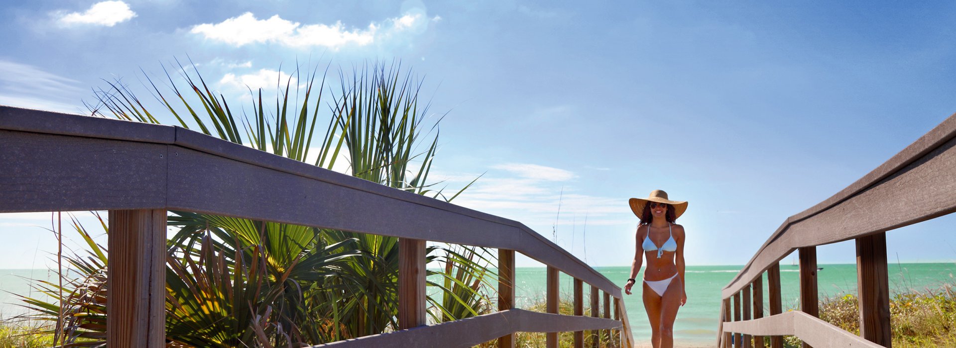 A young lady dressed in bikini walking Indian Rocks Beach boardwalk.