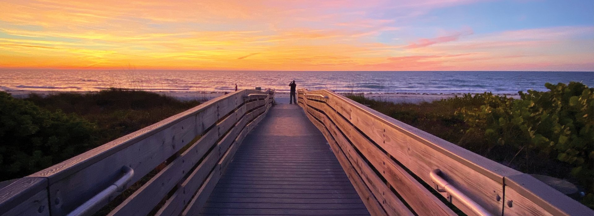 A man taking a photo of the colorful sunset in Indian Rocks Beach