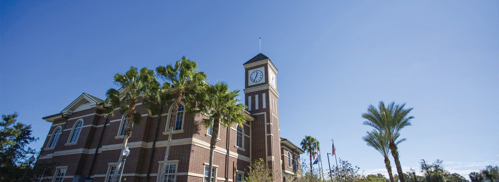 Pinellas Park train station exterior brick walls showing the clock at the top of the tower, blue skies and palm trees.