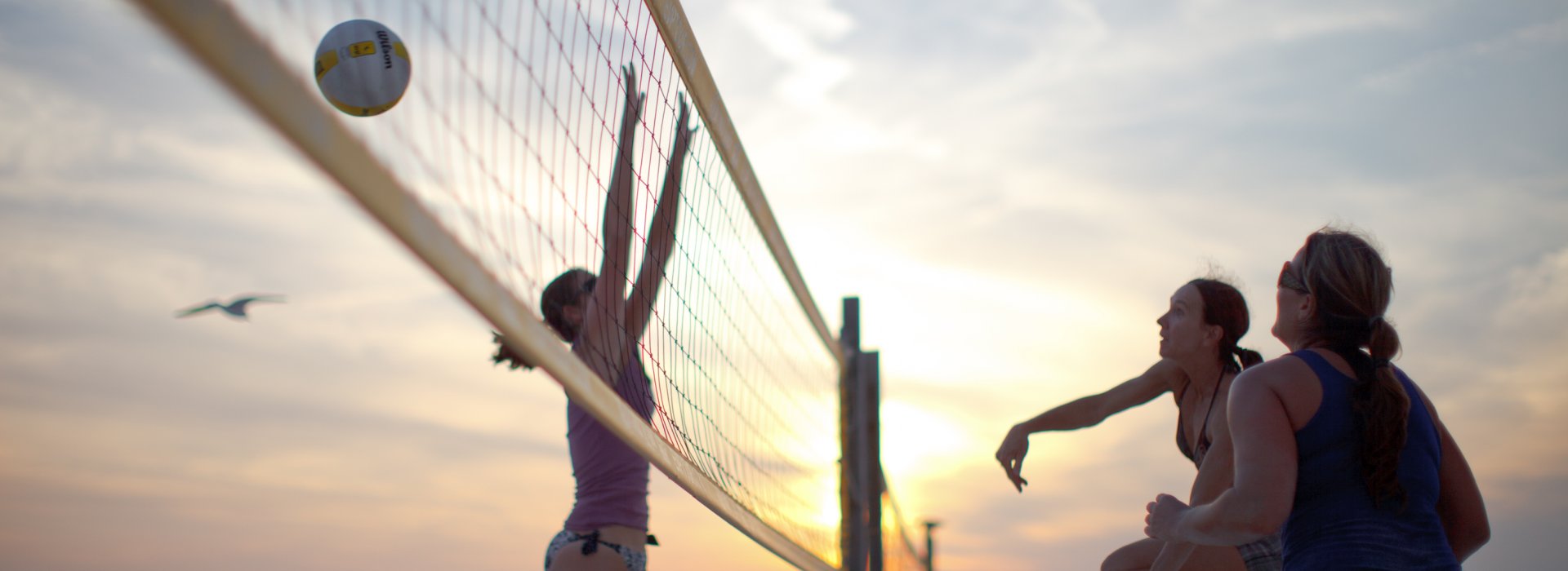 A group of woman play volleyball in St. Pete Beach as the sun sets.