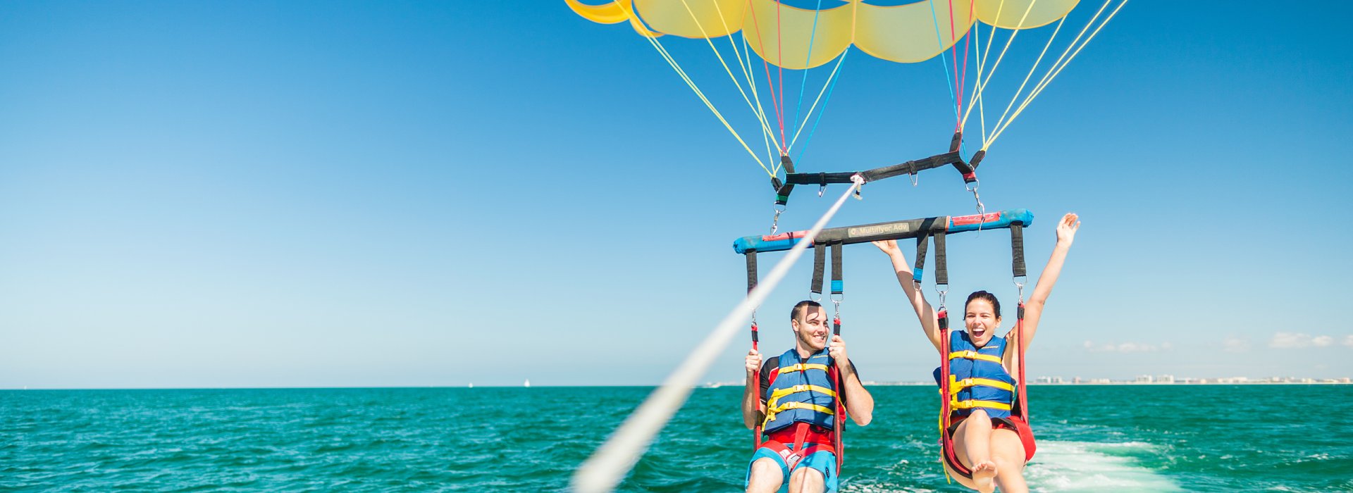 A couple taking flight in a parasail in Clearwater Beach.