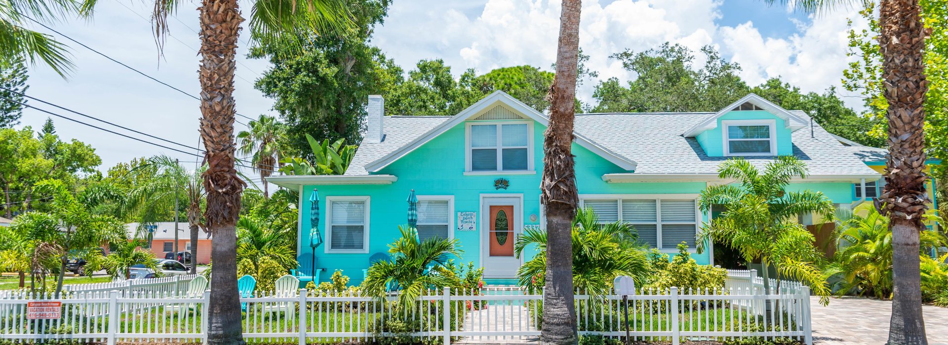 A blue house with palm trees around it seen from the road in Gulfport.