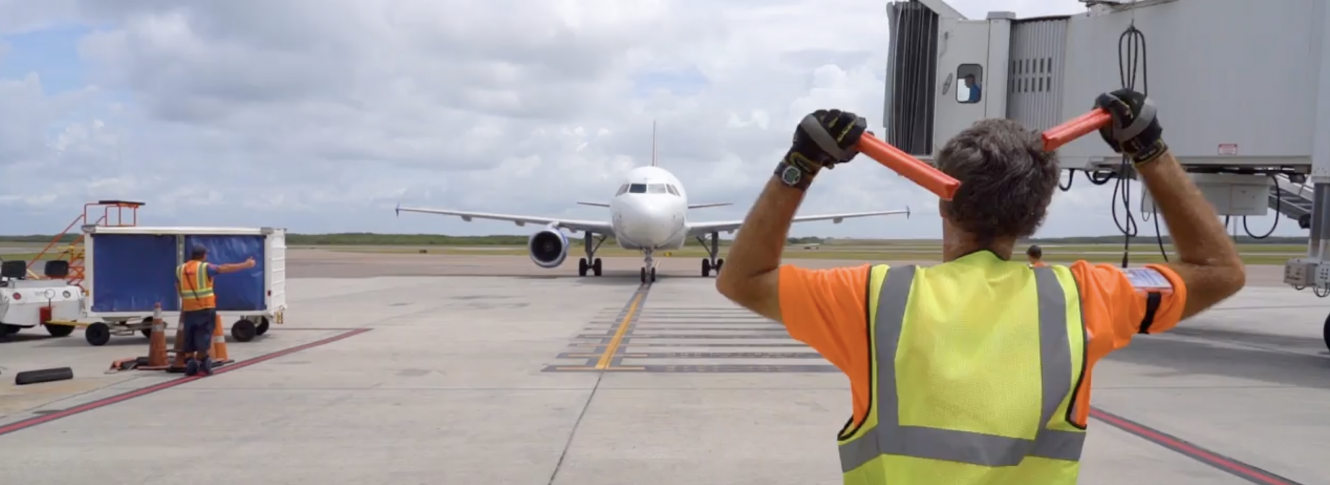 A flag person helping airplane taxing at airport