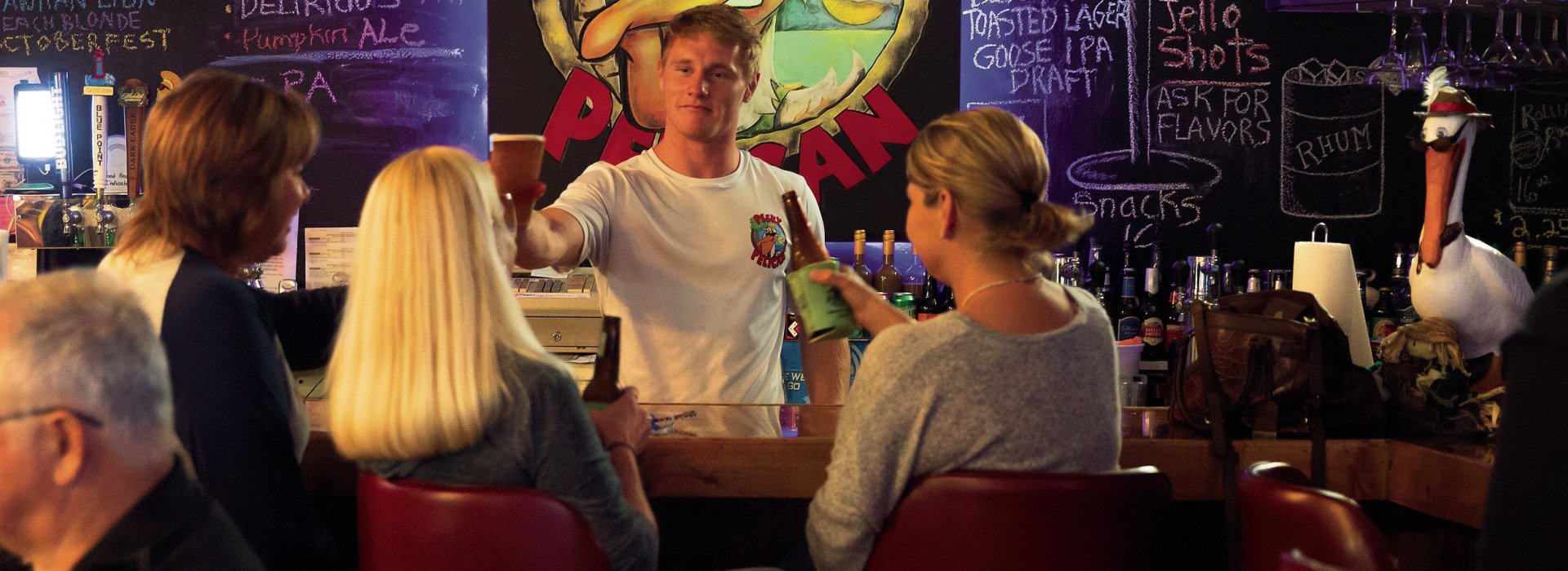 Few people toasting with the bartender at the bar of Pesky Pelican Brew Pub.
