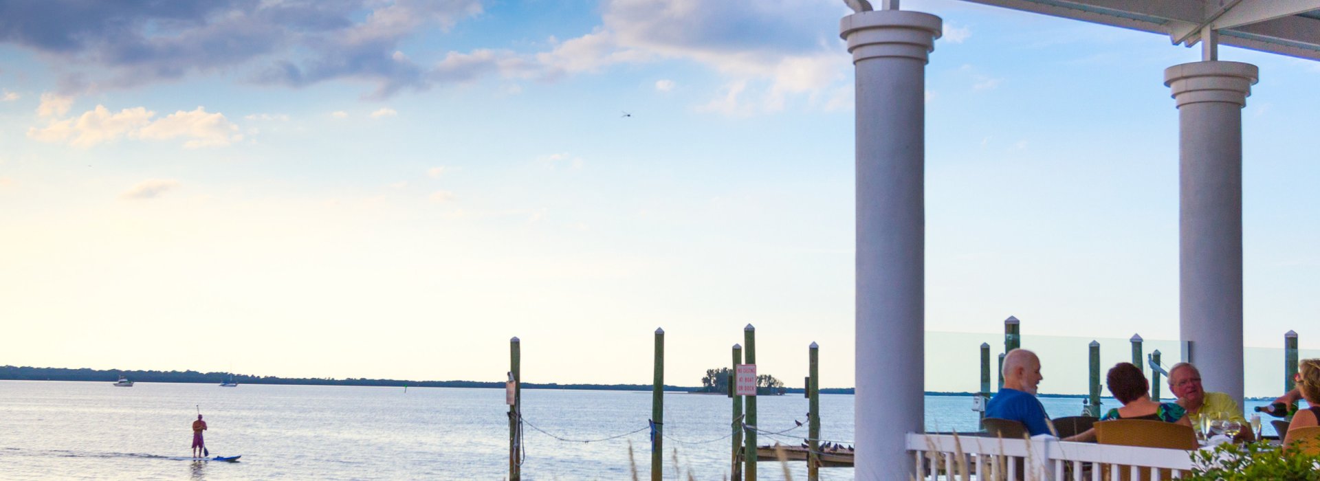 People dine on a waterfront deck at Bon Appetit in Dunedin at dusk