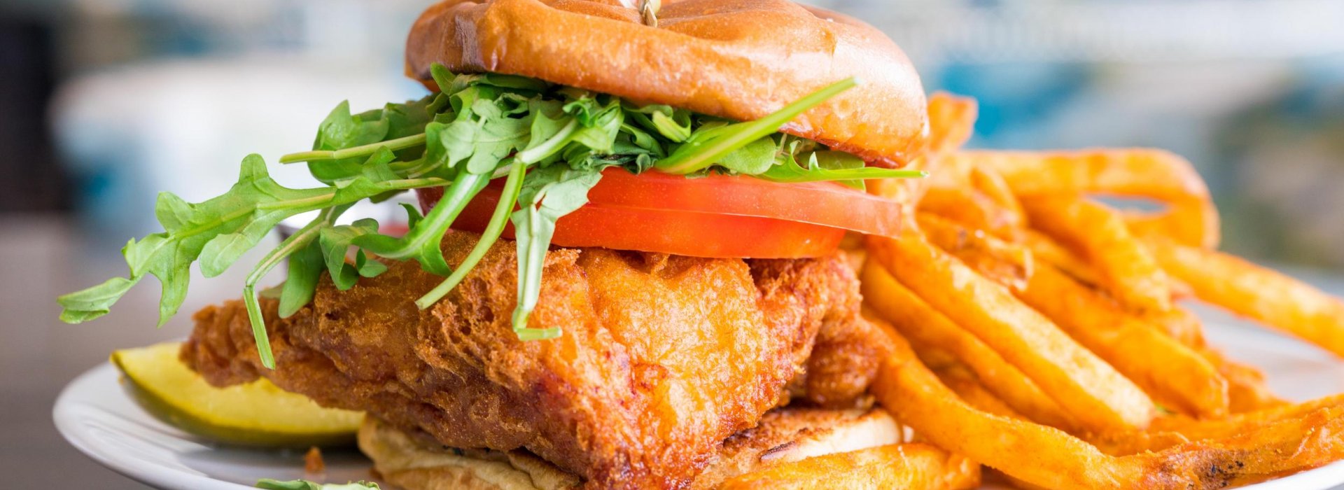 a beer-batter fried grouper sandwich with lettuce and tomatoes and fries on the side