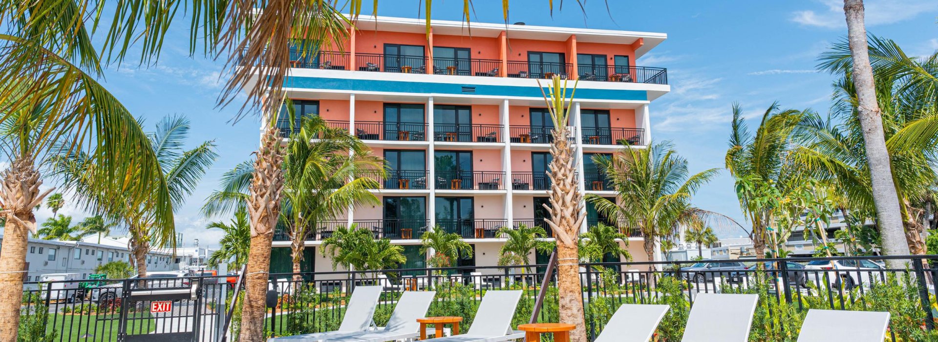 Eine Außenaufnahme des Hilton Garden Inn Hotel in St. Pete Beach mit markanten rosa und grünen Elementen.