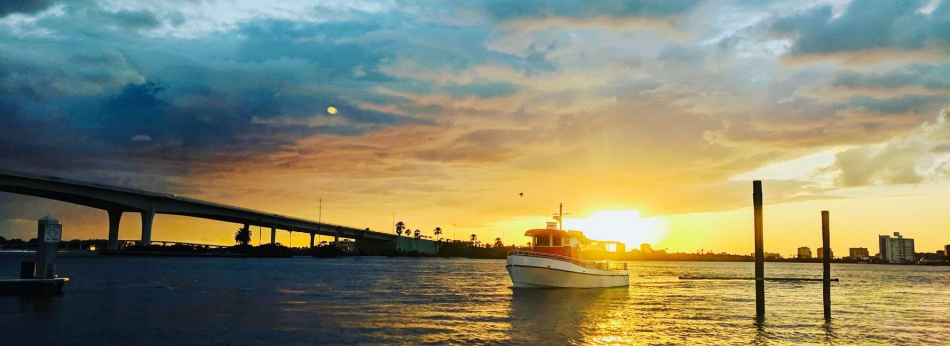 Little Toot Dolphin Adventure tour in Clearwater Beach featuring a boat on the water during sunset.