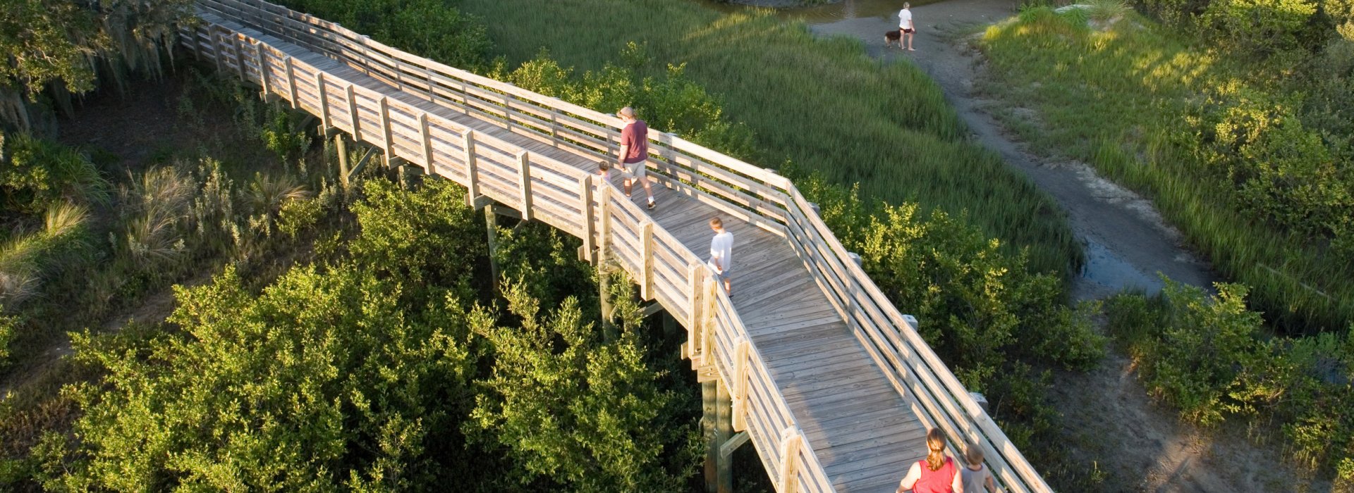 A wooden boardwalk with a few people walking through Boca Ciega Millennium Park