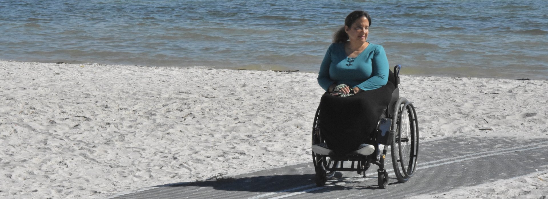 Woman in wheelchair on Mob-Mat on the beach