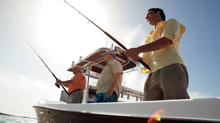 A group of men in a black boat fishing.