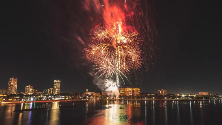 Fogos de artifício vermelhos e brancos explodem sobre o horizonte de St. Pete