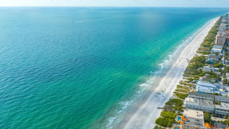 aerial view of Indian Rocks Beach lined with a strip of white sand beach and blue-green waters; hotels and condo buildings line the shore