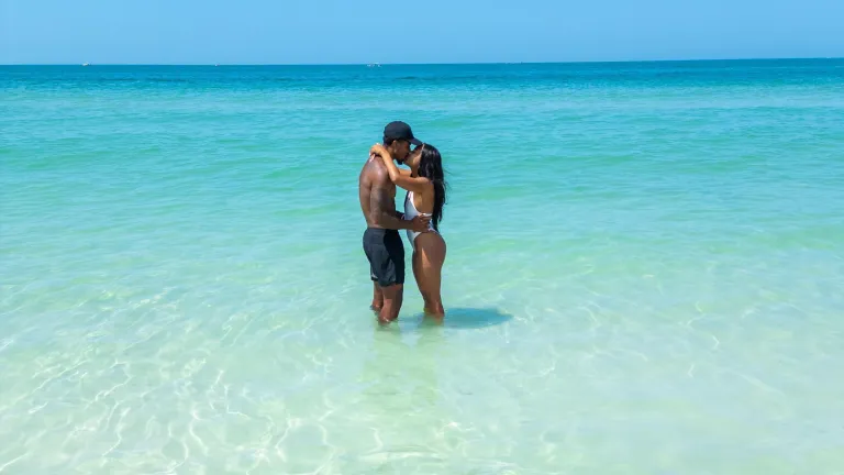 a couple kissing while standing in clear turquoise waters at the beach