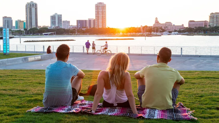 Three people on a blanket looking out over the water at the St. Pete Pier