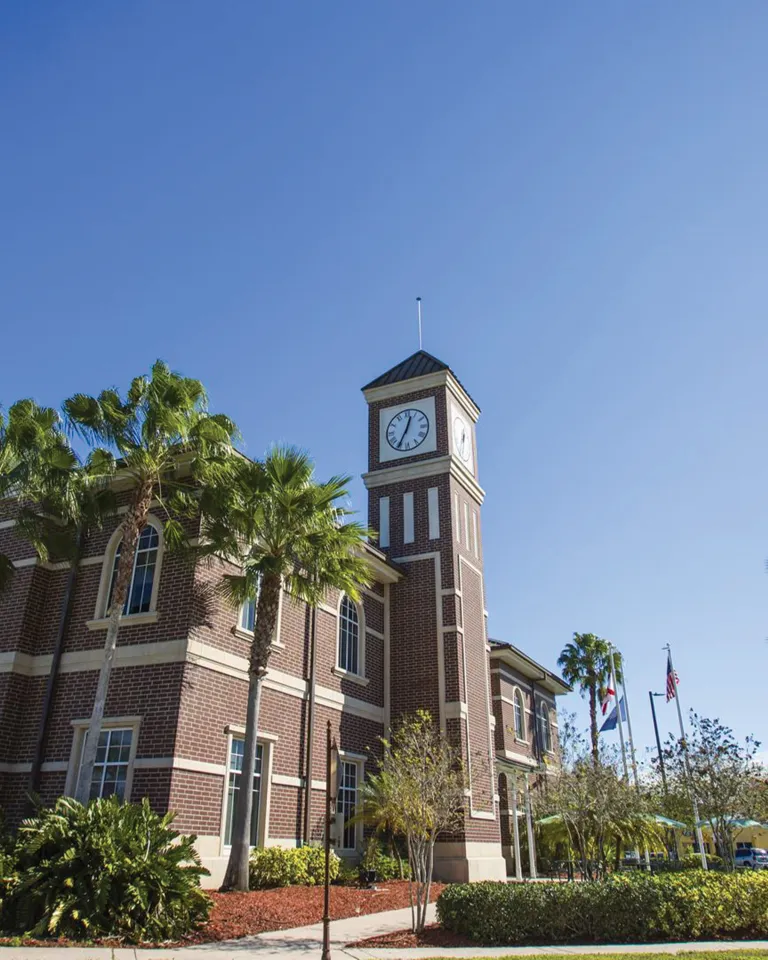 Pinellas Park train station exterior brick walls showing the clock at the top of the tower, blue skies and palm trees.