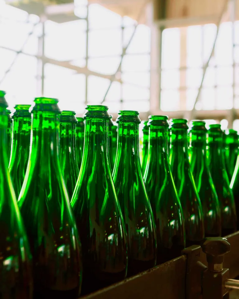 Several green beer glasses in line to be filled up in a brewery.