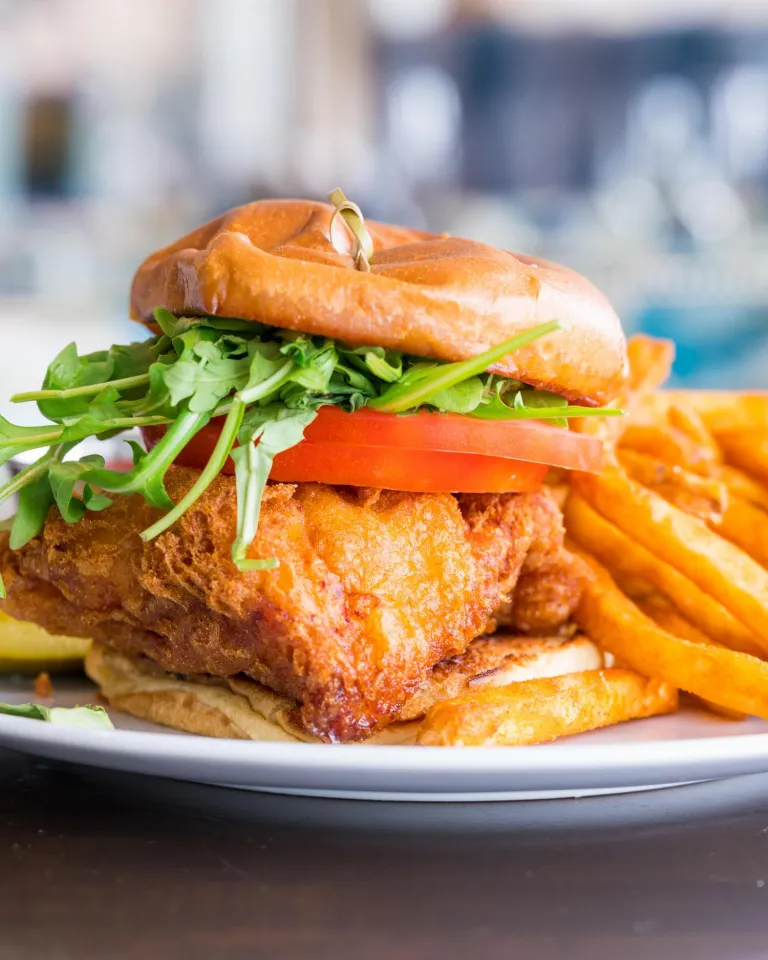 a beer-batter fried grouper sandwich with lettuce and tomatoes and fries on the side