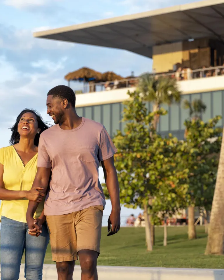 Casal de mãos dadas em frente ao prédio do St. Pete Pier