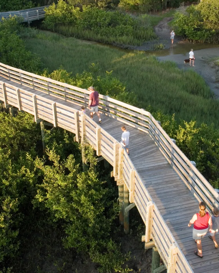 A wooden boardwalk with a few people walking through Boca Ciega Millennium Park