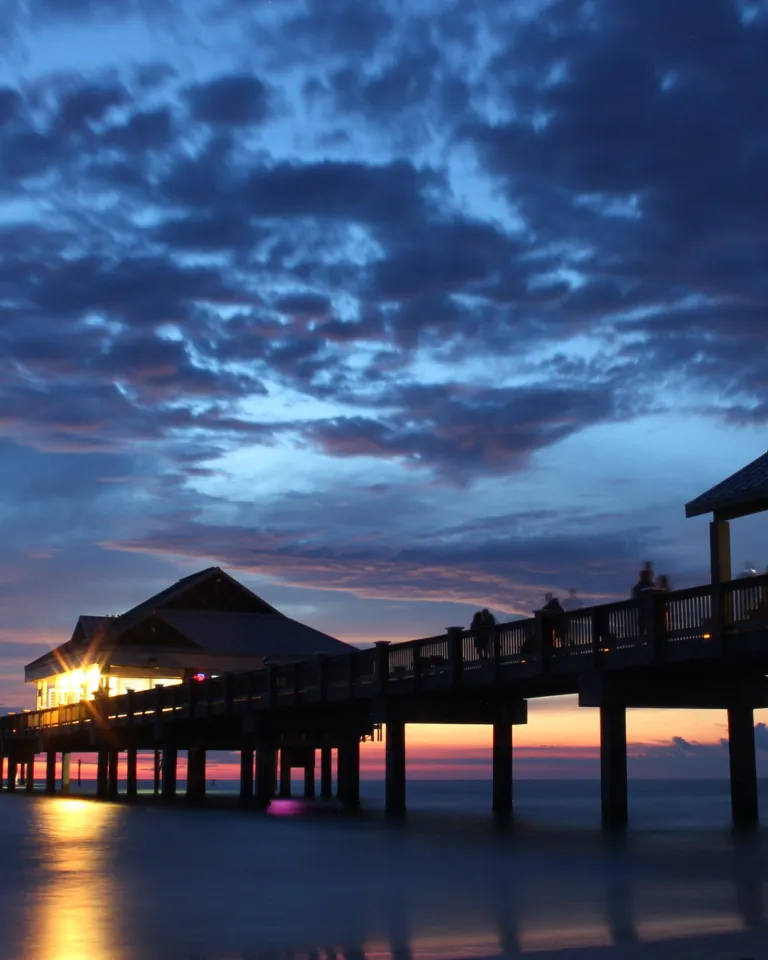 deep blue and purple sunset with clouds over Pier 60 which is illuminated by lights underneath
