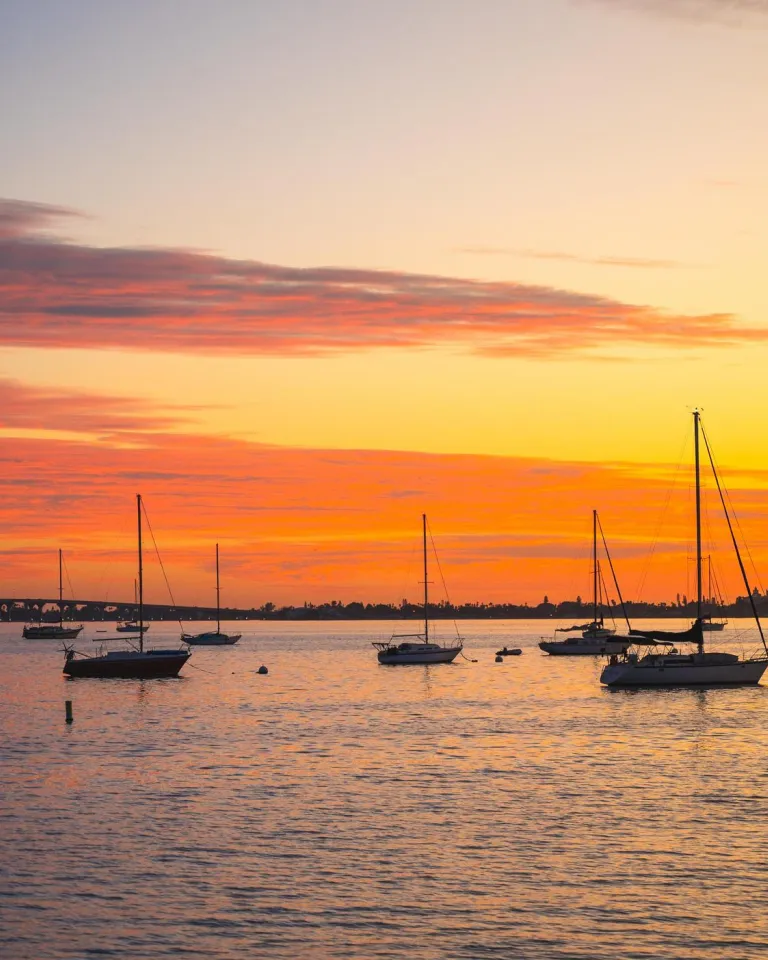 a brilliant orange and yellow sunset with sailboats anchored in the bay in Gulfport