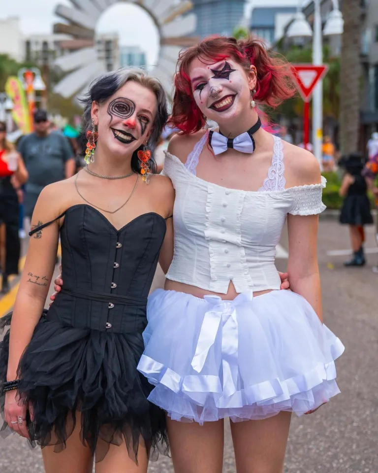 two women dressed up in costumes with a crowd of people behind them at the Halloween on Central event in St. Petersburg FL