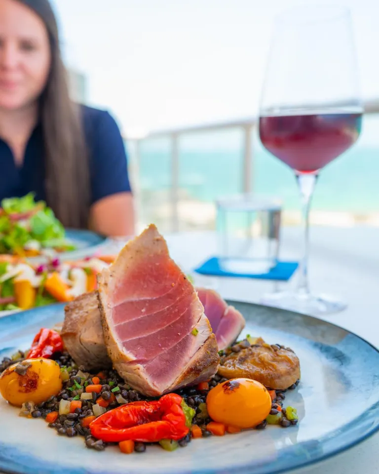 a beautifully presented plate with vegetables and rare ahi tuna at a gulfront table at Ocean Seven at the Hiatus Hotel