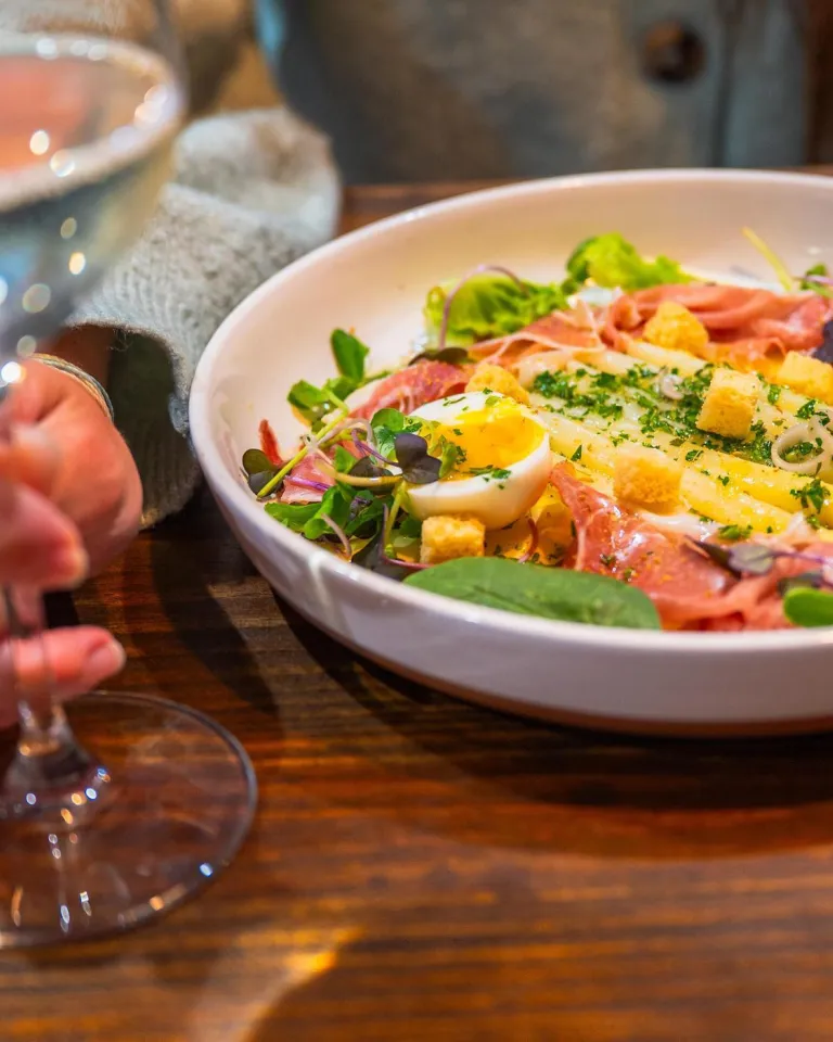 a woman having a salad and a glass of wine at The Restorative in Dunedin