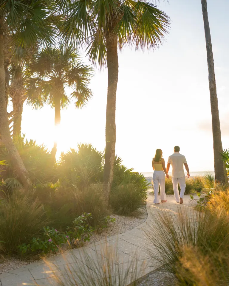 A couple walks out to the beach from Gulfside Resorts